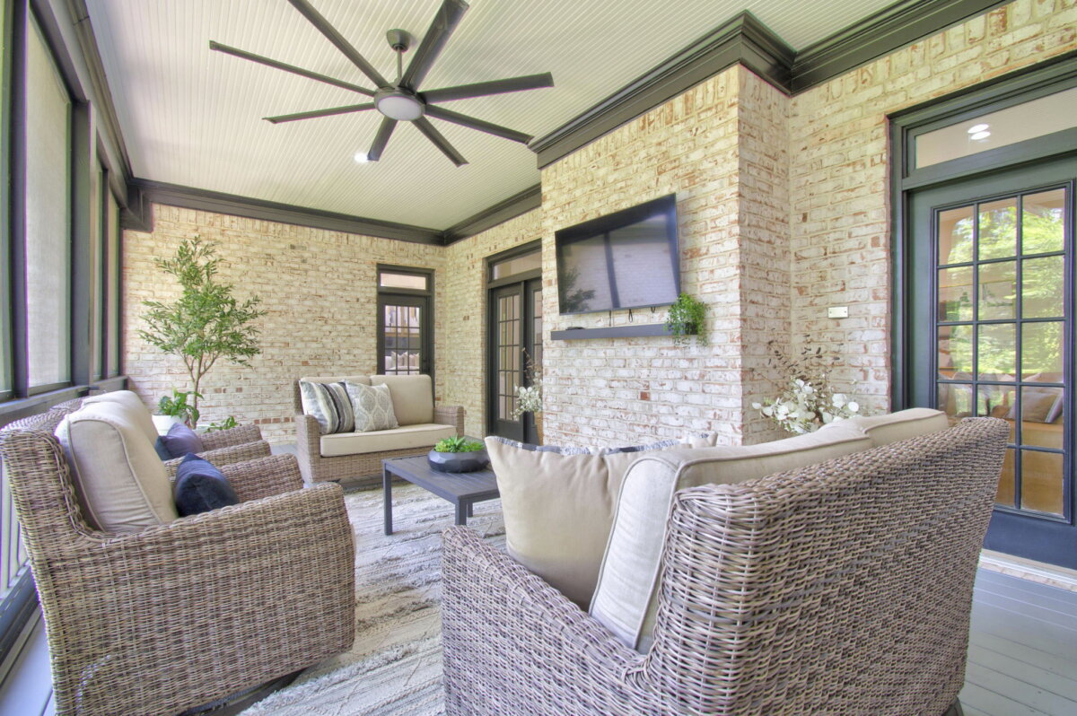 Just Listed! This Renovated Brentwood Home Has a Private Primary Wing, 4 Fireplaces & a Park-Like Backyard - 8 Screened-in porch with wicker furniture, neutral cushions, a wall-mounted TV, ceiling fan, potted plants, and brick walls with black trim. Large windows let in natural light and offer picturesque views of the park-like backyardβa perfect retreat in your beautifully renovated Brentwood home.