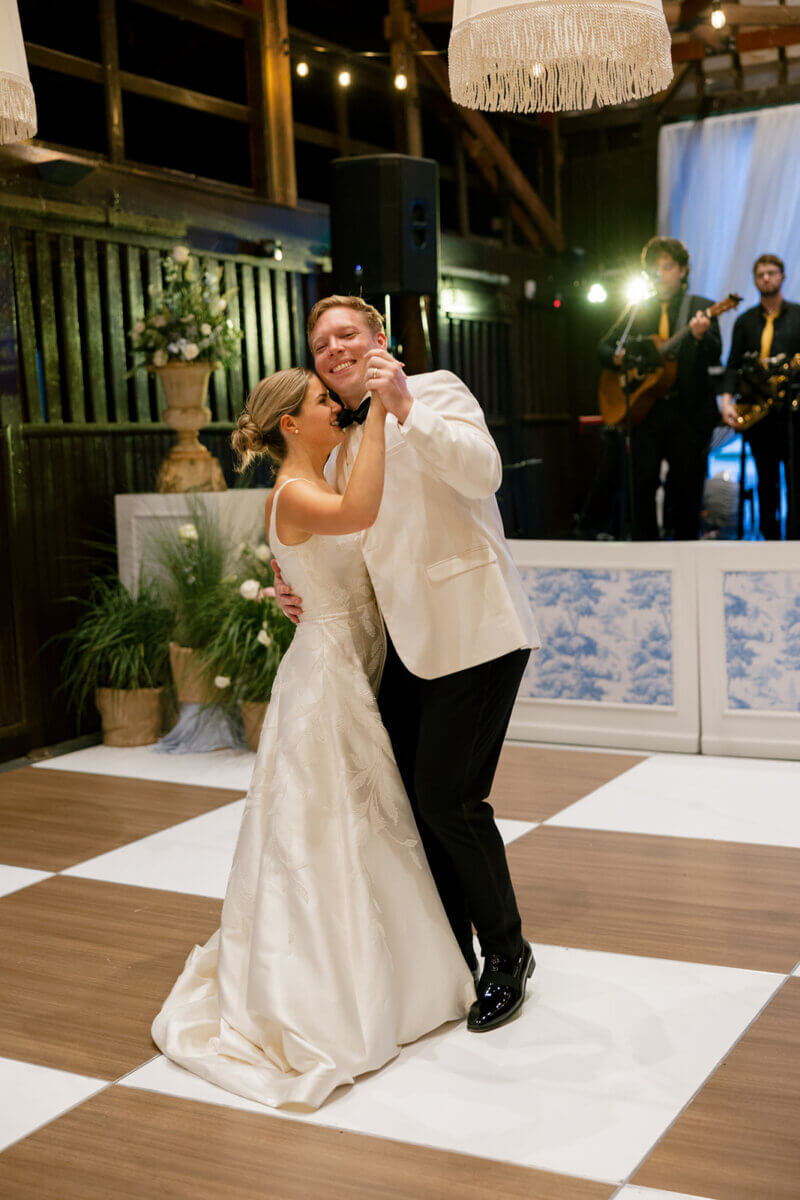This Dreamy Equestrian Wedding Made History at Franklin's Harlinsdale Farm - 13 A bride and groom dance together on a checkered floor at their wedding reception at Harlinsdale Farm in Franklin, with a live band performing in the background.