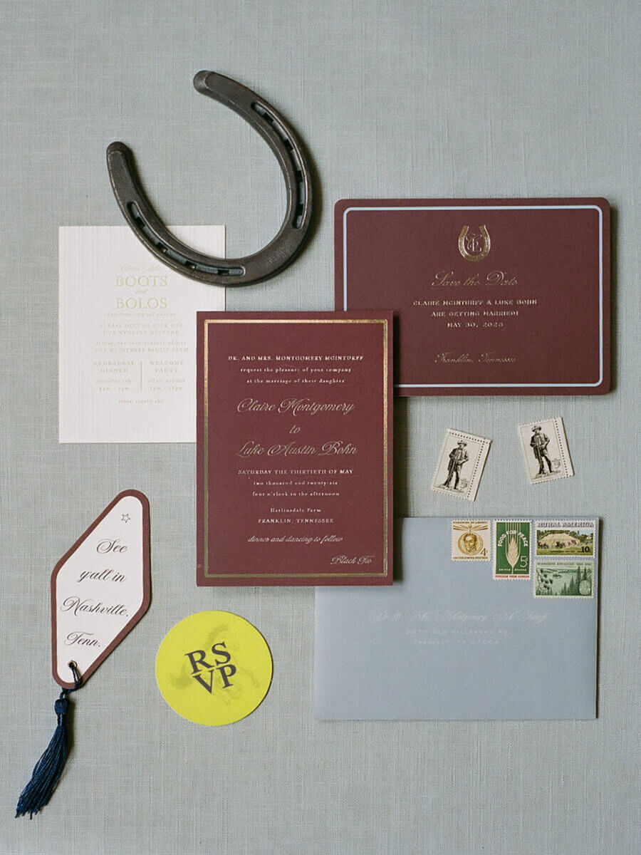 This Dreamy Equestrian Wedding Made History at Franklin's Harlinsdale Farm - 4 Flat lay of wedding invitation suite with RSVP card, stamped envelope, stamps, horseshoe, tag reading "Meet y'all in Nashville," and event details for a Harlinsdale Farm wedding in Franklin—all styled on a neutral background.