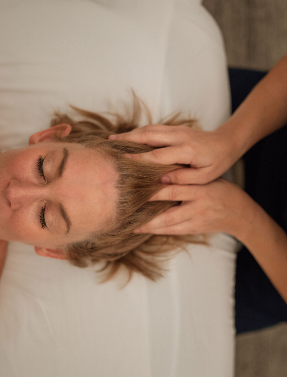 Person lying on a massage table receiving a head massage, with hands gently pressing on their scalp—enjoying one of the best Nashville Deals for relaxation and wellness.
