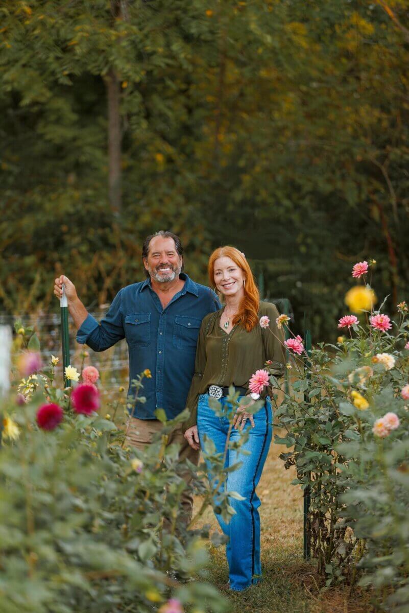 12 Beautiful U-Pick Flower Farms Near Nashville - 8 A man and a woman stand together in a flower garden at one of Nashville’s charming U-Pick Flower Farms, surrounded by blooming flowers and greenery, smiling at the camera.