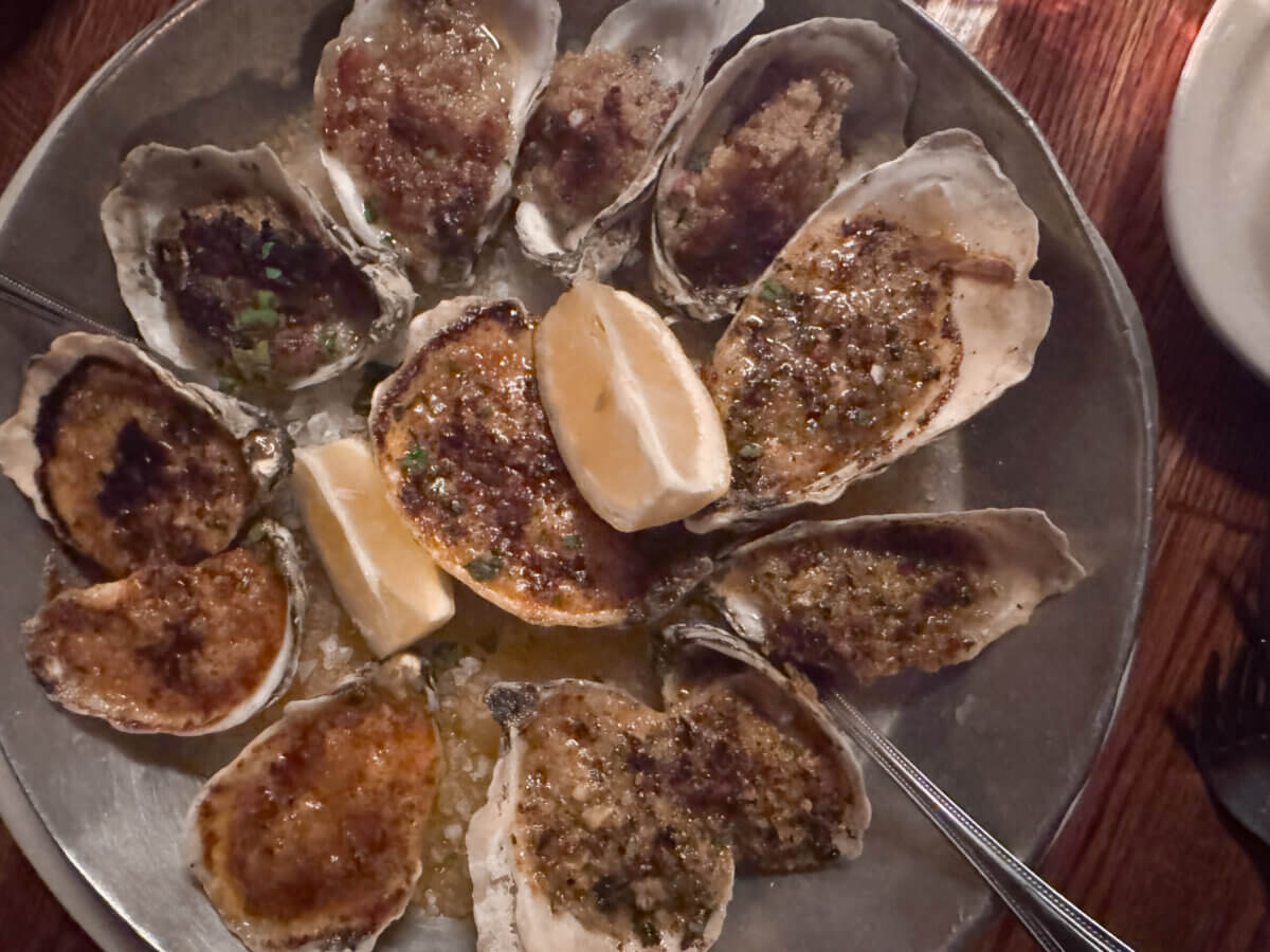 An Ode to Oxford: How to Eat Your Way Through This Delicious Small Town - 14 A metal plate of baked oysters topped with herbs and breadcrumbs, arranged around two lemon wedges.
