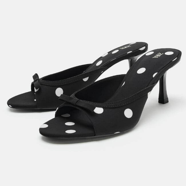 Polka Dots Are Everywhere. Here Are The Pieces We're Loving! - 20 A pair of black open-toe heeled mules with white polka dots and a small front bow detail, perfect for adding a touch of playful fashion trends to your wardrobe.