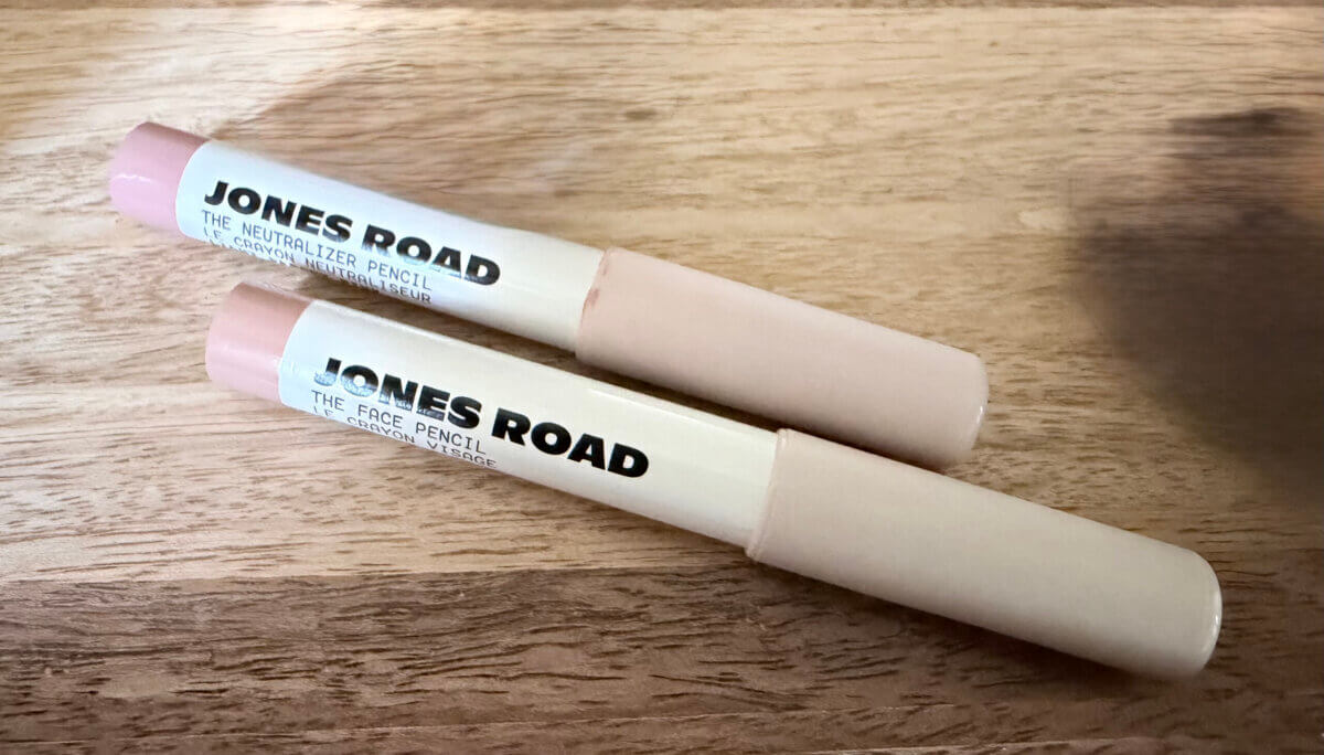 Bobbi Brown's Essential Makeup Musts for Every Decade - 7 Two Jones Road makeup pencils, labeled "The Neutralizer Pencil" and "The Face Pencil," lie parallel on a wooden surface