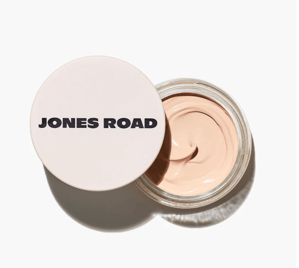 Bobbi Brown's Essential Makeup Musts for Every Decade - 8 Open jar of light beige cream makeup with "JONES ROAD" printed in bold black letters on the lid, set against a white background.
