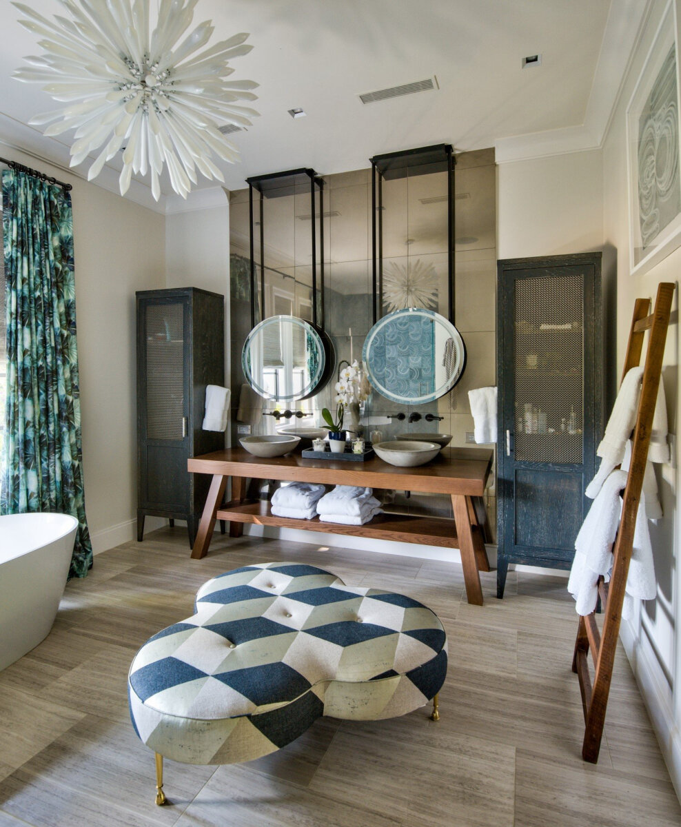 This Designer Wrote the Book on Creating Colorful Spaces — Literally! - 10 Modern bathroom design, featuring a double vanity, two round mirrors, glass cabinets, a patterned ottoman, freestanding tub, ladder towel rack, and floral chandelier.