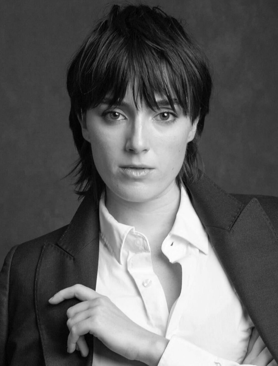 Meet the Memphis Designer Behind the Eerie World of "Obsession" - 2 Black and white portrait of a Memphian with short, tousled hair, wearing a white button-up shirt and a dark blazer, looking directly at the camera with a neutral expression, crafted with striking attention to detail.