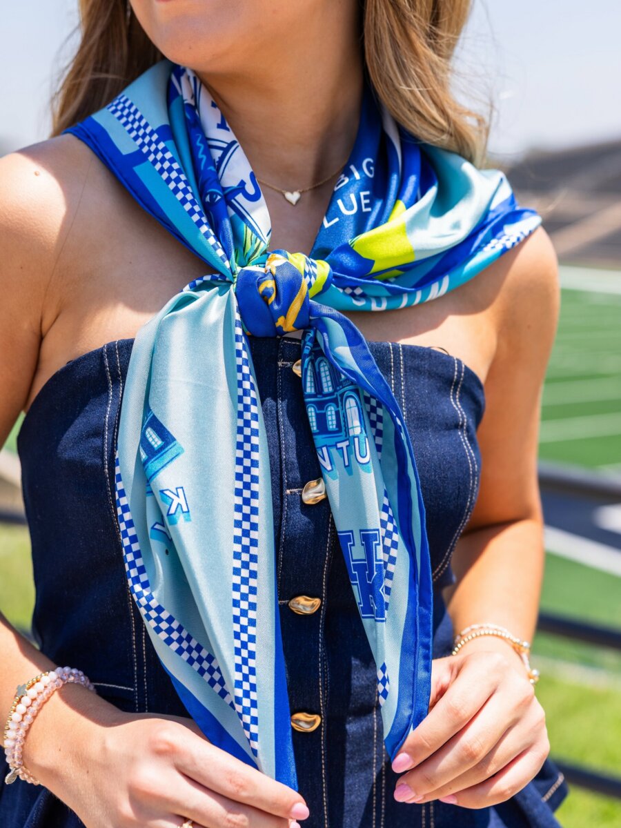 Southern Brands to Know for Football Season: Clothing, Decor & More - 2 Woman wearing a colorful scarf with patterns, the perfect accessory for Football Season, draped over a strapless denim dress, standing near a sports field.