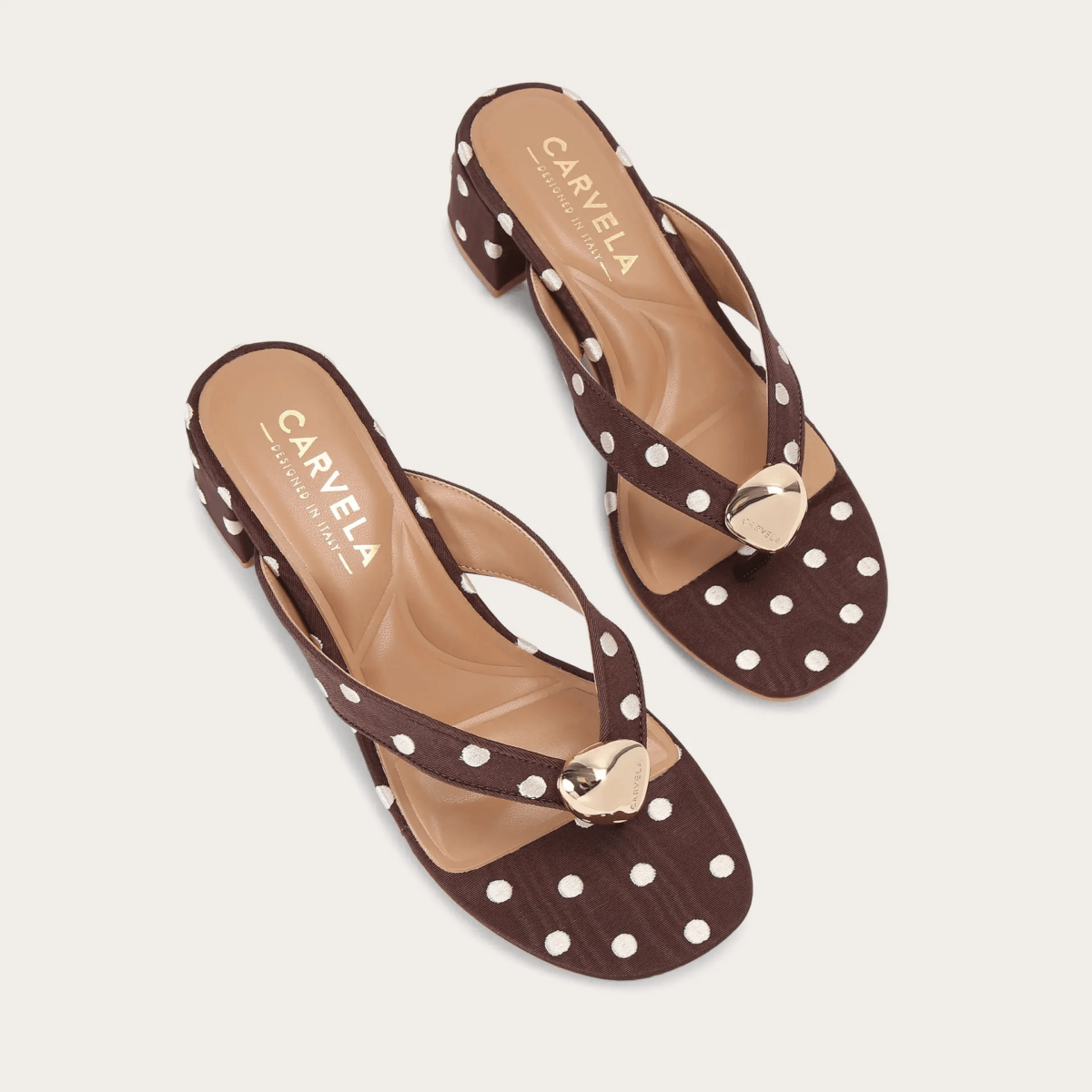 A pair of brown polka dot heeled sandals by Carvela, featuring gold circular embellishments on the straps—perfect to wear for a bold fashion statement.
