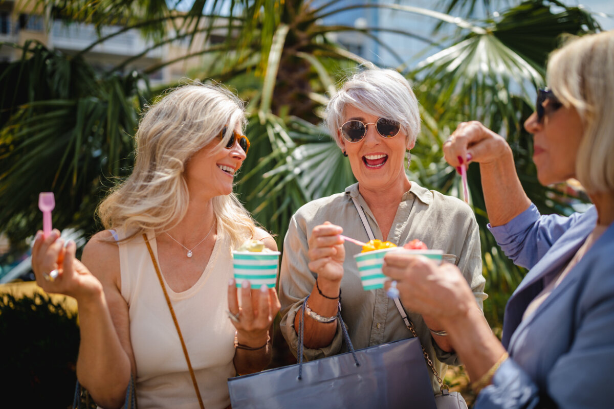 Why "Good" Finance Advice Doesn't Work for Everyone - 3 Three women with light hair, wearing sunglasses, eat ice cream outdoors near palm trees, smiling and talking together as they share stories about misunderstood financial advice.