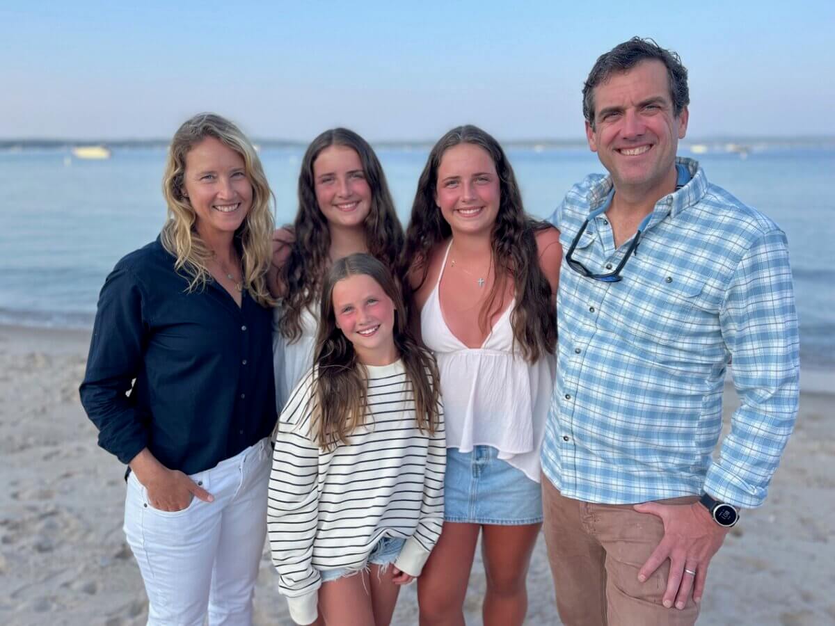 This Nashville Author Sees the Extraordinary in Ordinary Words - 4 Five people stand together on a sandy beach near the water, smiling at the camera on a clear dayβcapturing a joyful moment with Varina Buntin Willse.
