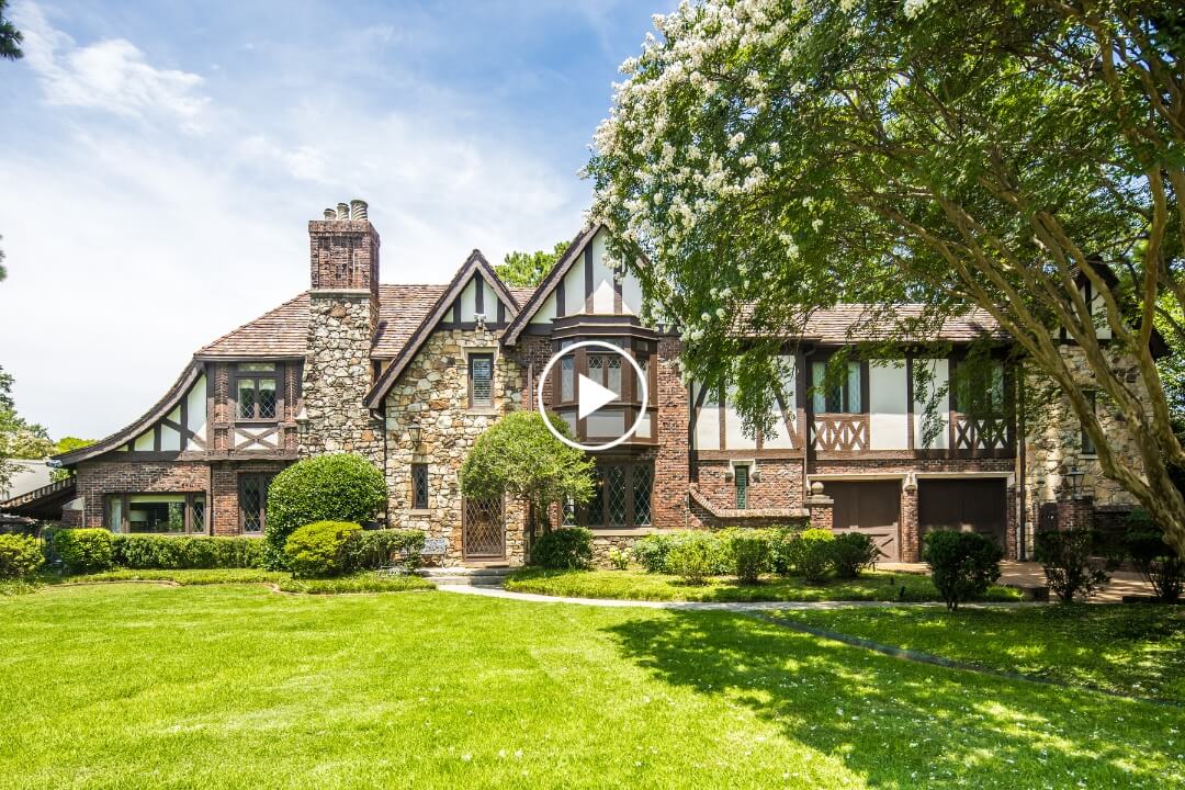 Large Tudor-style house with stone and brick exterior, gabled roof, tall chimney, and a well-maintained front lawn with mature trees on a sunny day, located at 226 W Goodwyn St in Memphis, TN.