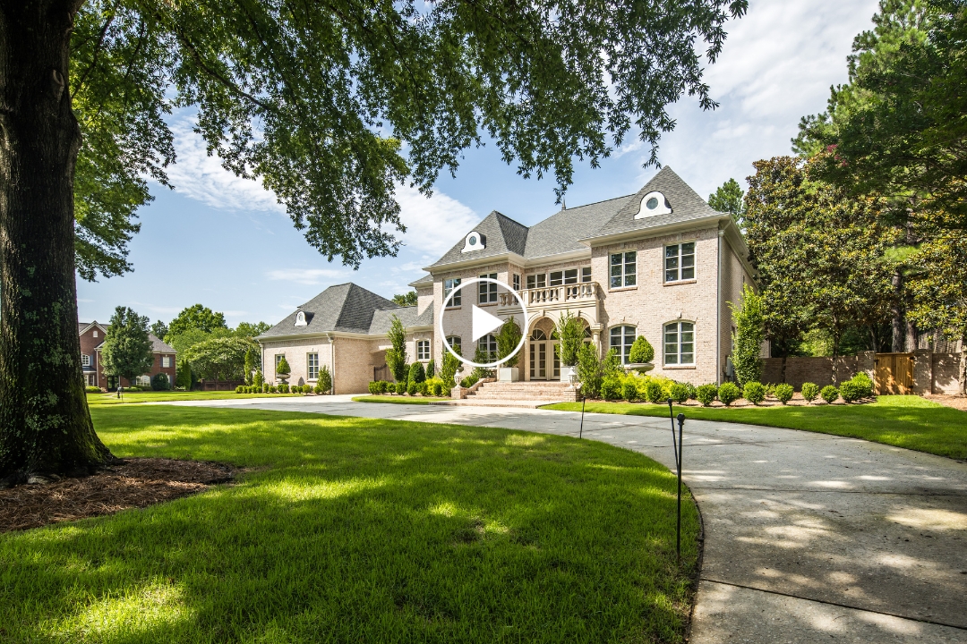 Large two-story brick house with dormer windows, a circular driveway, manicured lawn, and trees on a sunny day, beautifully situated at 2720 Calkins Rd in Germantown TN—a stunning example of Germantown real estate.