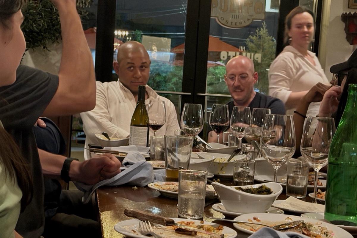 An Unexpected Meal in Jackson, MS, Inspired Our Newest Summer Salad - 2 A group of people sit around a restaurant table with empty plates, glasses, and bottles, engaged in conversation.