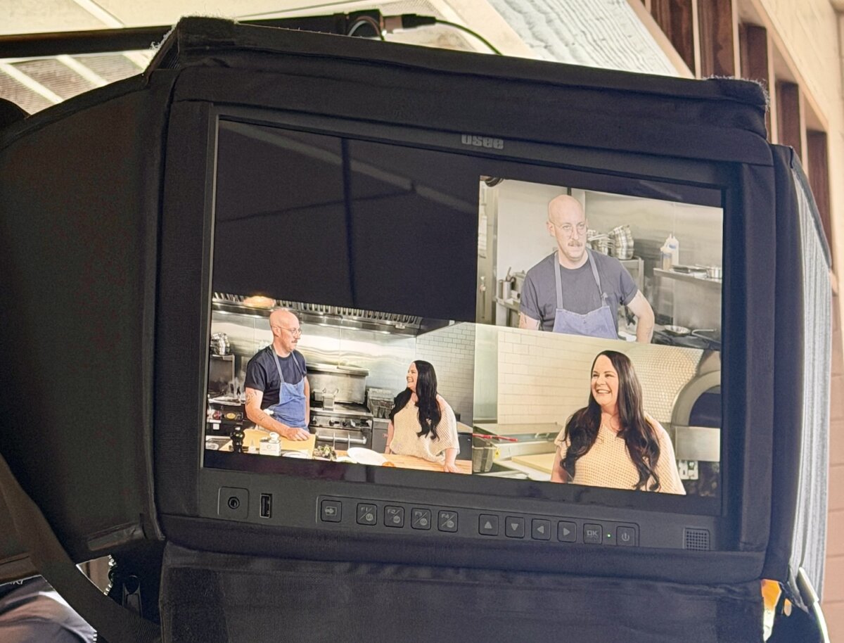 An Unexpected Meal in Jackson, MS, Inspired Our Newest Summer Salad - 3 A monitor displays three camera angles showing a man and a woman in a kitchen setting in Jackson MS, engaged in conversation and cooking a meal.