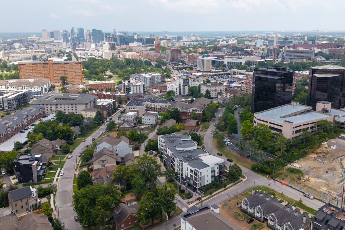 Aerial view of 3116 W End Cir, Nashville, TN, with residential neighborhoods in the foreground and tall office buildings and downtown skyscrapers in the background on a partly cloudy day.