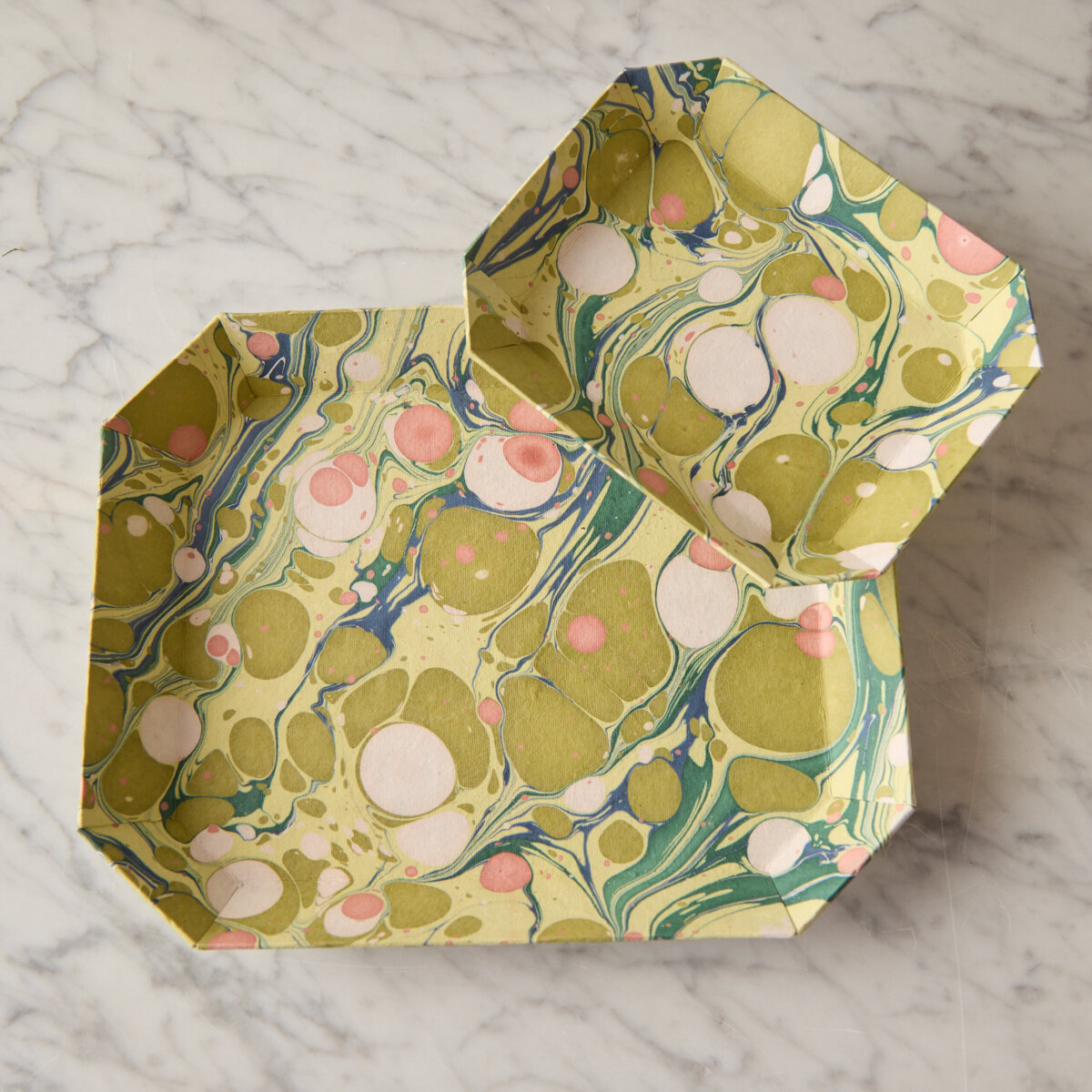 A Nashville Tastemaker on Table-Setting Do's and Don'ts, Hosting Disasters, and More - 5 Two rectangular trays with marbled green, pink, and blue patterns sit on a white marble surface, offering vibrant inspiration for unique tablescape ideas.