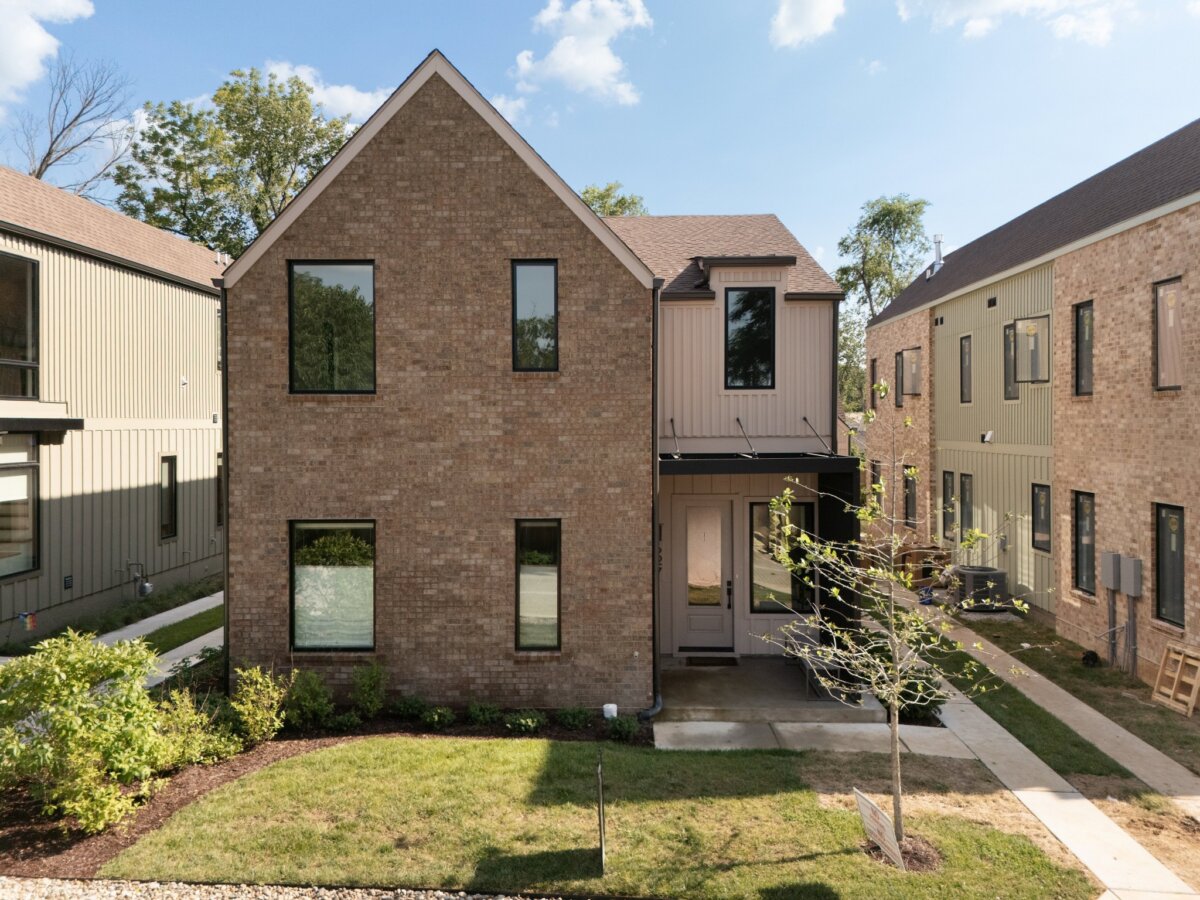 A modern two-story brick house with black-framed windows, a small front porch, and minimal landscaping on a sunny day, perfectly captures the contemporary charm of 627 Richmond Bend in Nashville.