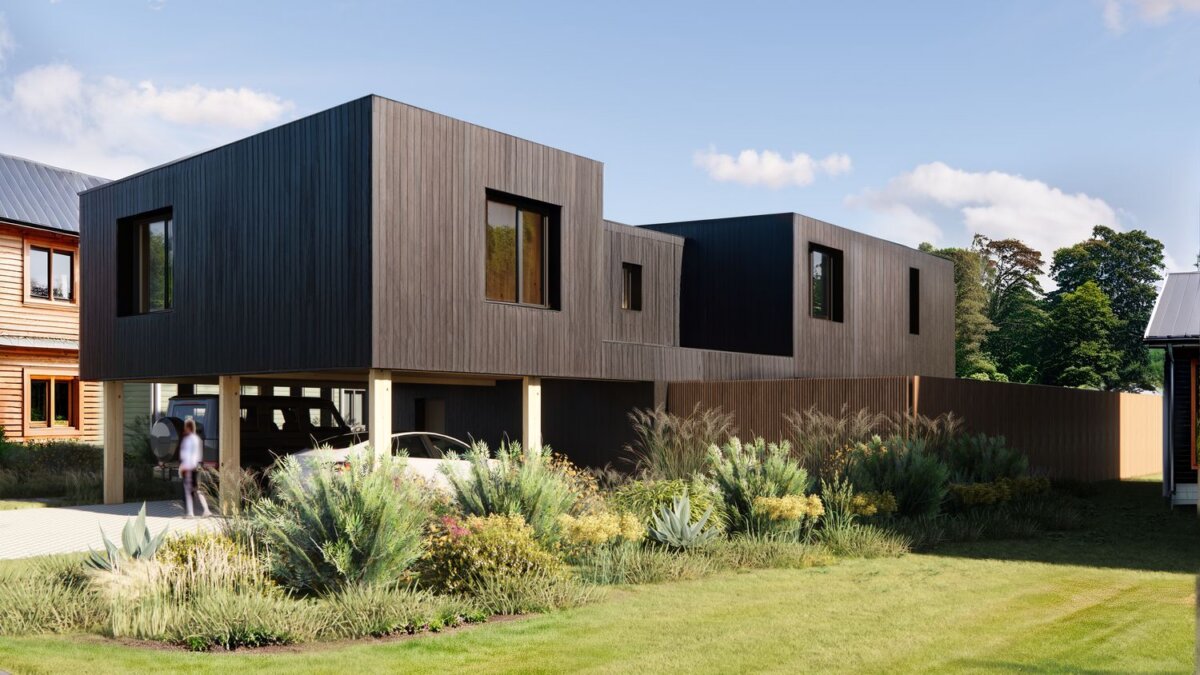 Modern two-story house with dark wood siding, large windows, and an open carport below. Located on N Jenna Ct Lot 28 in Nashville, this home is surrounded by green landscaping and neighboring homes under a clear sky.