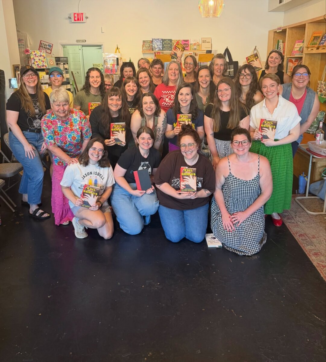 8 Ways to Meet New People in BHAM - 3 A group of people pose at Thank You Books, many holding books and smiling, in a bookstore with shelves of colorful books in the background.