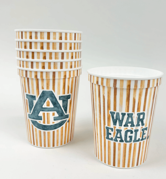 A stack of striped paper cups with the Auburn University logo, perfect for Fall Football Weekends, sits beside a cup with “War Eagle” text, both on a white background.