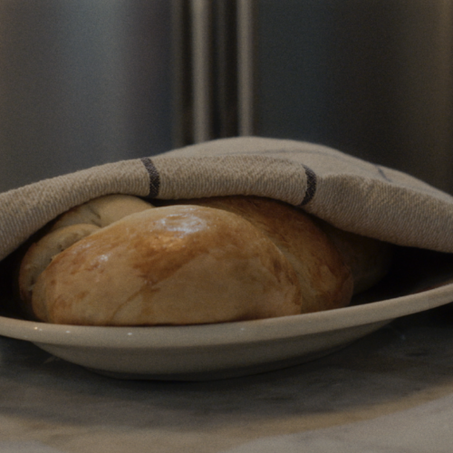 How Food & Family Carried One Alabama Woman Through IVF (+ 3 Recipes) - 5 A plate of bread rolls is partially covered with a beige cloth on a kitchen counter, offering a warm, homemade touch as if inspired by cherished family recipes, with a refrigerator and other kitchen items in the background.