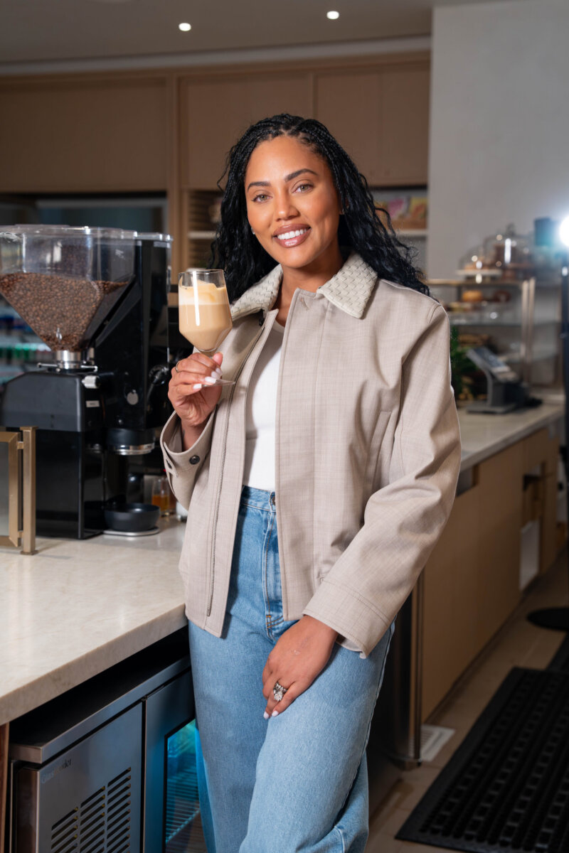 Ayesha Curry holds a glass with coffee in it.