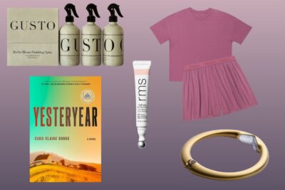 A flat lay of home spray bottles, a pink pajama set, a gold bracelet, a book titled “Yesteryear,” and a tube of RMS lip product on a purple gradient background—this curated selection earns its place on the sb hot list.