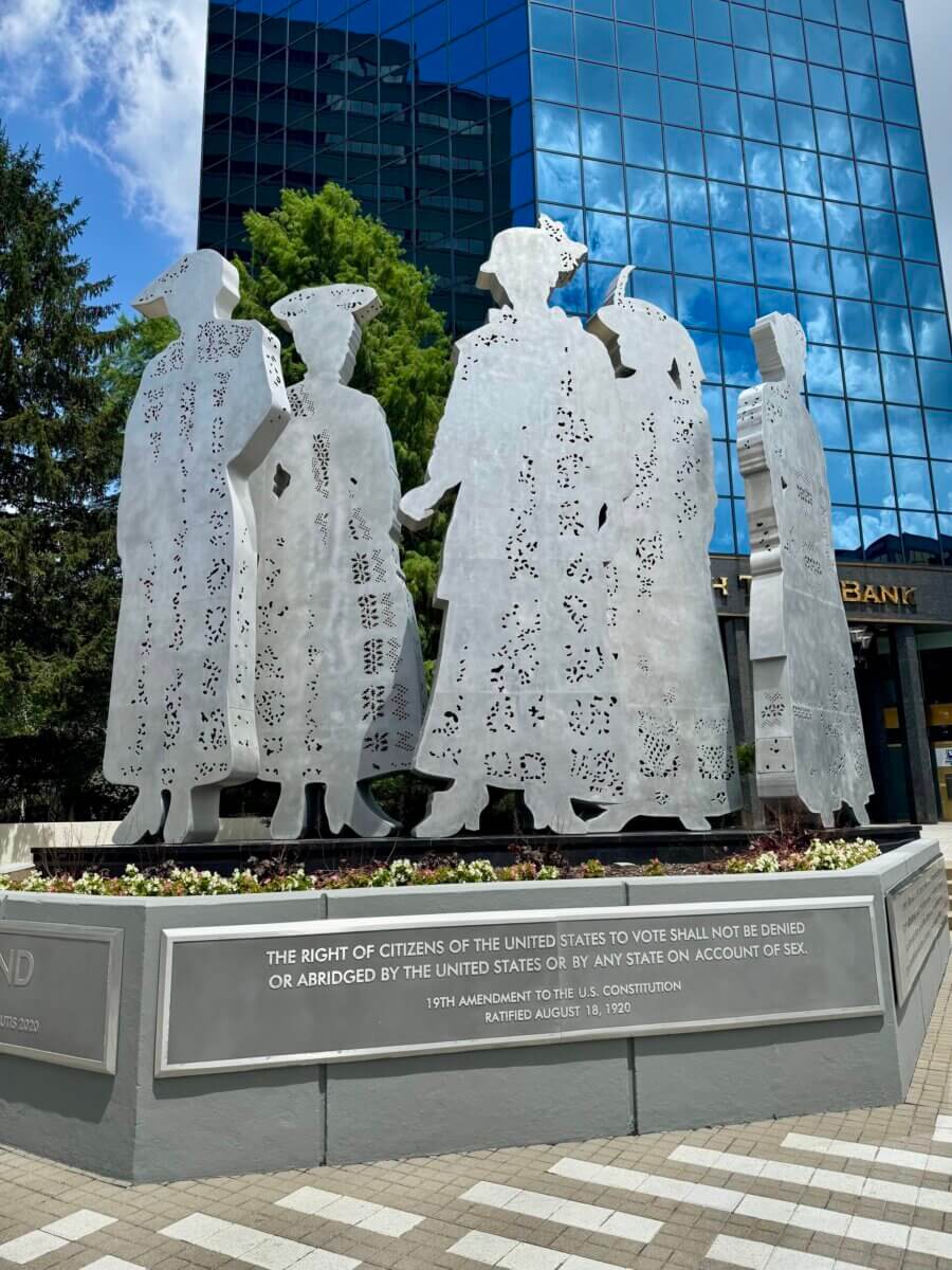 The Best of Lexington, KY: Iconic Stops + Hidden Gems - 5 Metal sculptures of five women in historic attire stand before a city building in Lexington, the Horse Capital of the World, with a plaque referencing the 19th Amendment granting women’s suffrage in the United States.