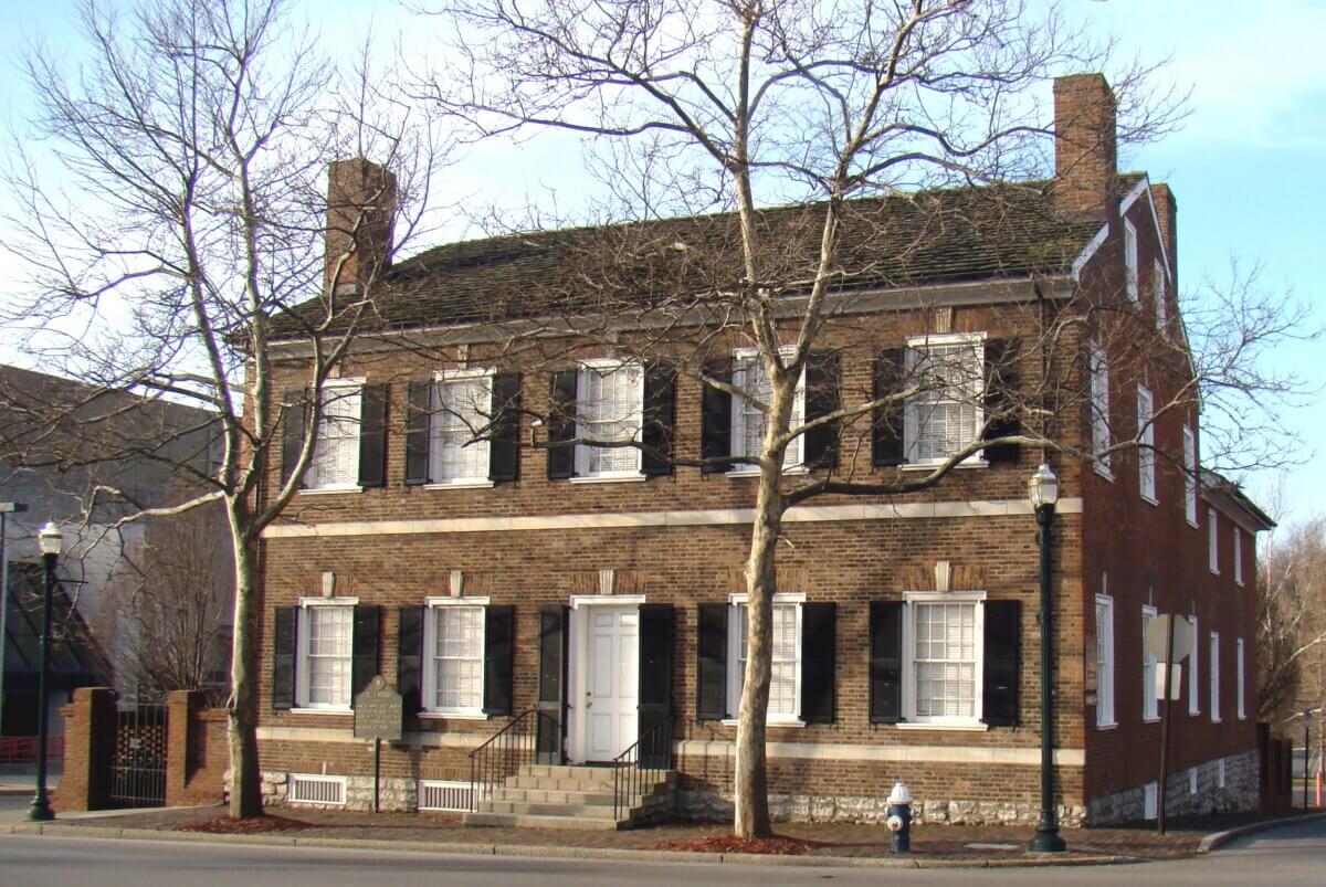 The Best of Lexington, KY: Iconic Stops + Hidden Gems - 4 Two-story brick building with black shutters, white trim, chimneys at each end, white front door, and leafless trees in front, located on a street corner in Lexington—the heart of Horse Capital country.