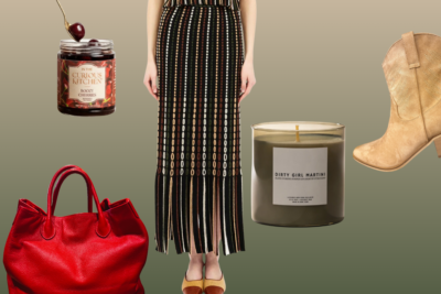 A mannequin in a black top and patterned skirt is surrounded by a red bag, boots, a jar of cherries, and a candle labeled “Dirty Girl Martini” on a gradient background.