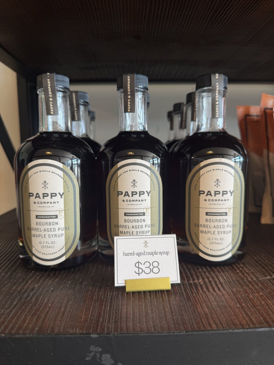 Three bottles of Pappy bourbon barrel-aged pure maple syrup are displayed on a shelf, priced at $38 each.
