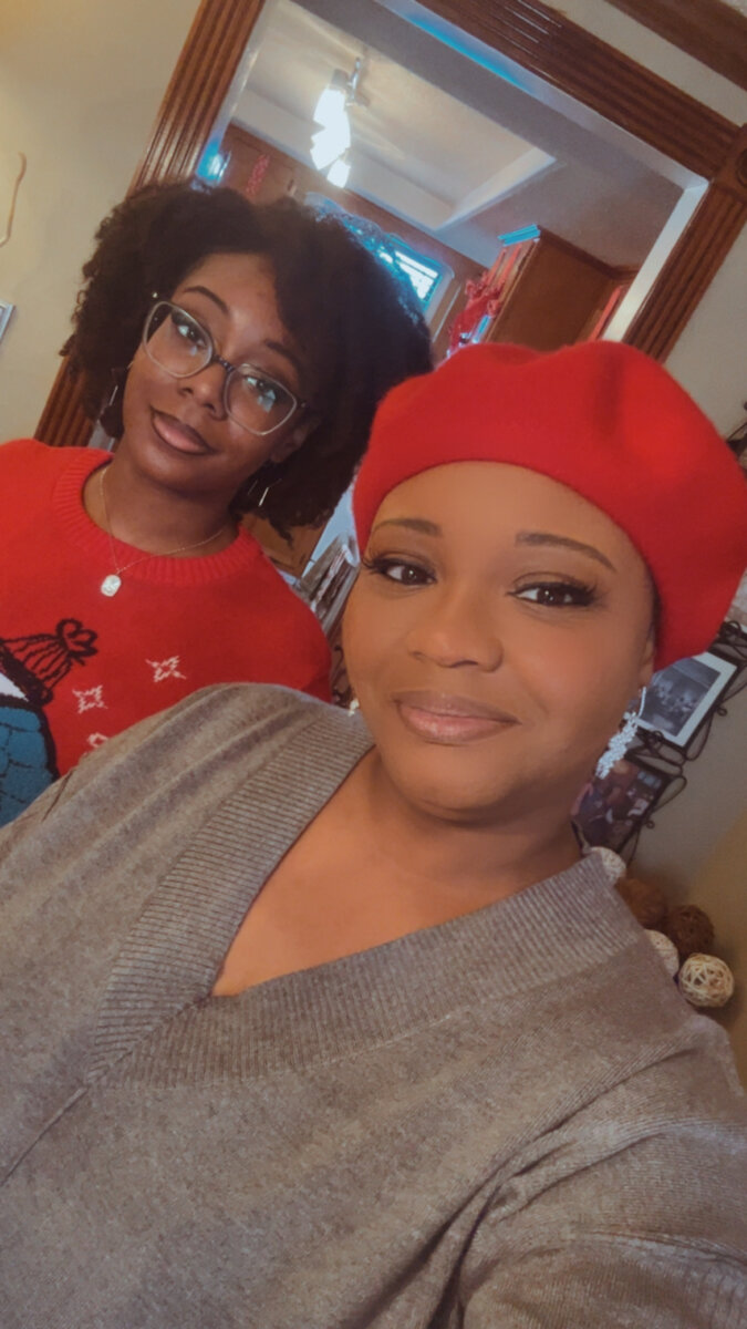 Two women, one in a red beret smile in a selfie.