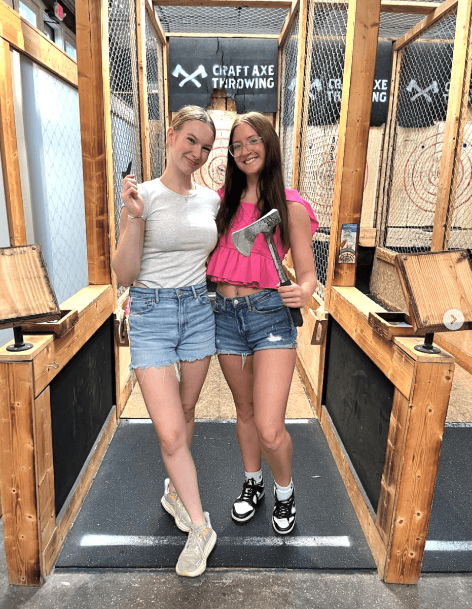 It's Playtime, Memphis! Here's Where to Get Your Game On - 3 Two women stand in front of axe throwing lanes, each holding an axe. Both are dressed casually in shorts and sneakers, smiling at the camera. Signs behind them read “Craft Axe Throwing.”.