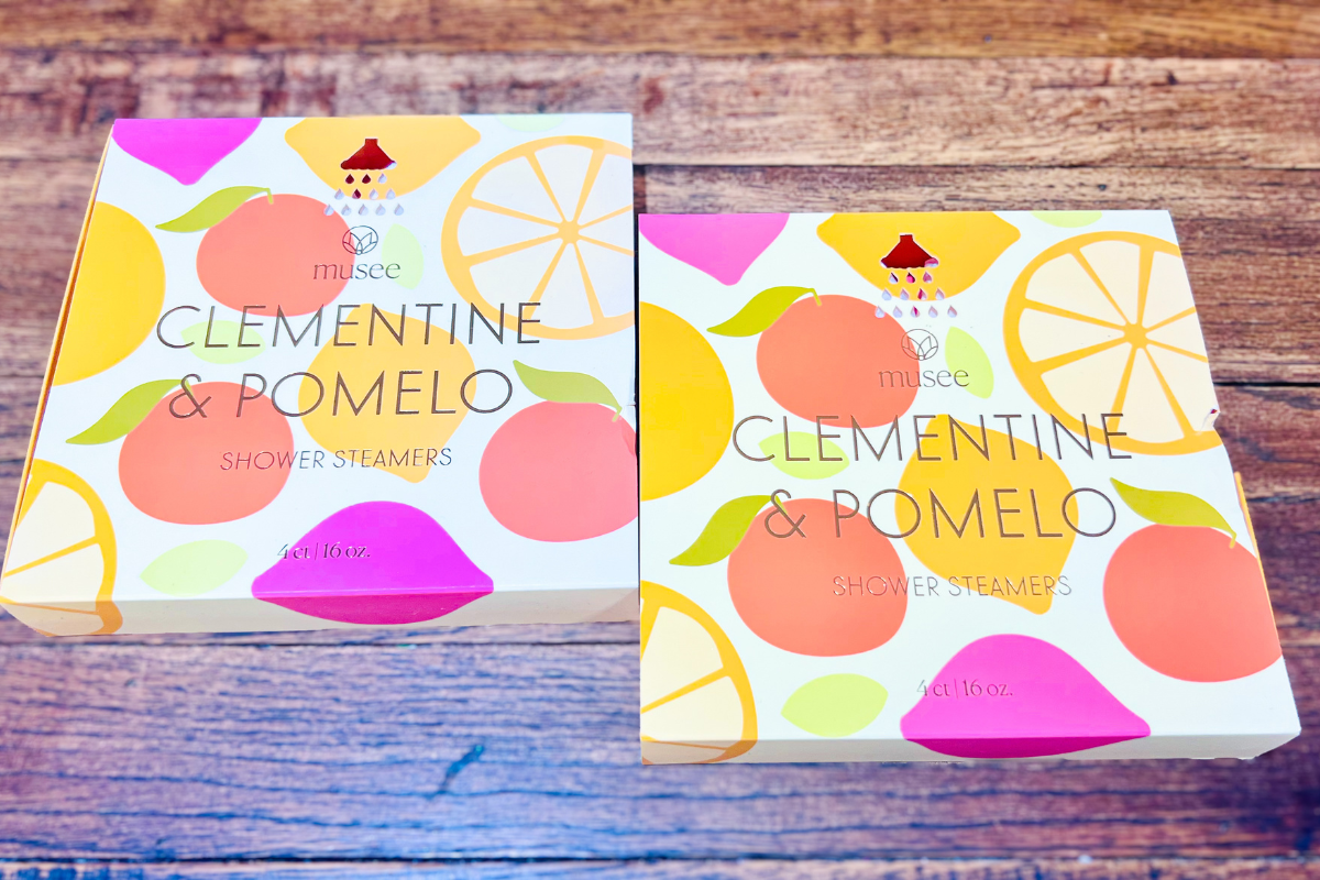 Two boxes of Musee Clementine & Pomelo Shower Steamers with colorful fruit illustrations on a wooden surface.