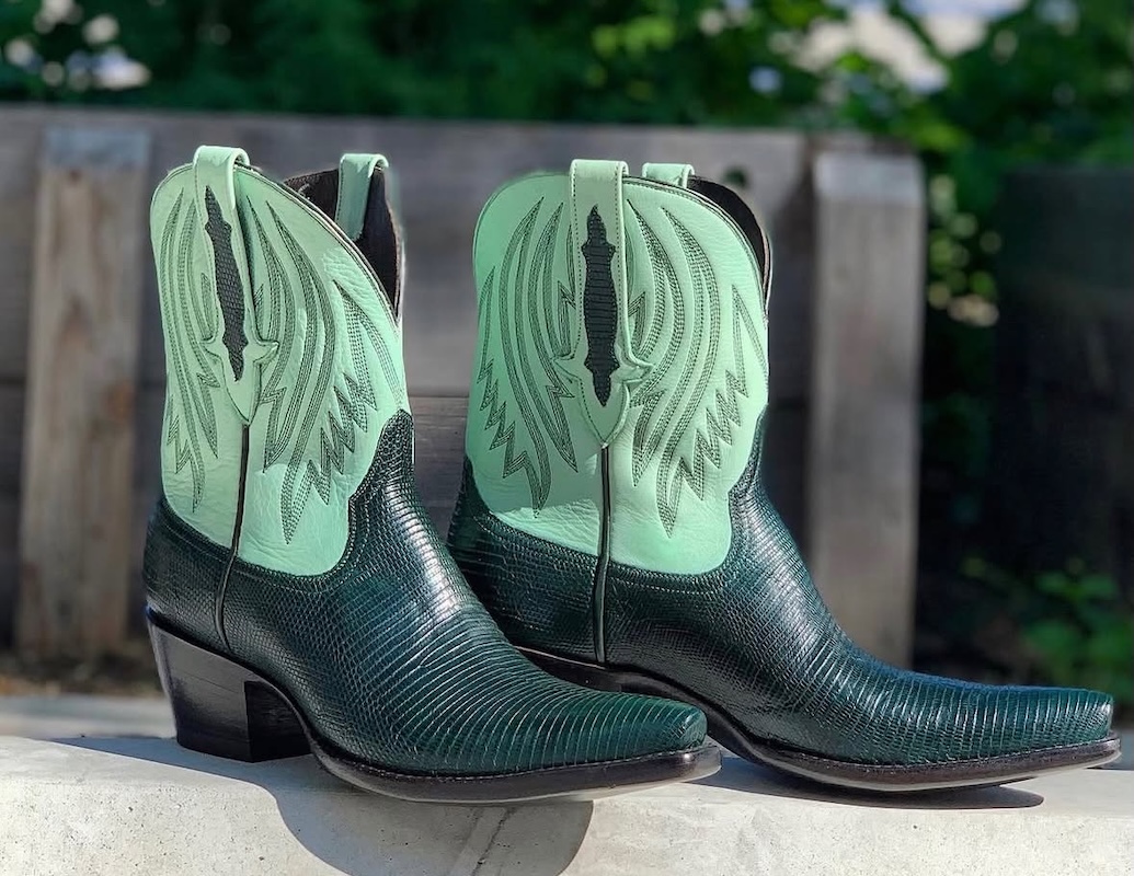 9 New Nashville Retail Spots to Explore - 7 A pair of cowboy boots with black textured leather and pale green tops featuring decorative stitching, displayed outdoorsβperfect for exploring new spots in Nashville or adding standout style to your retail collection.