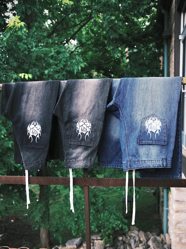 9 New Nashville Retail Spots to Explore - 9 Three pairs of jeans with white tribal designs on the back pockets hang over a railing outdoors, with green trees in the backgroundβa stylish snapshot perfect for showcasing the latest finds from Nashville shopping and new retail spots.