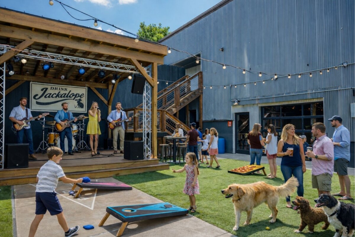 Dogs and children play in a grassy area where a band plays.