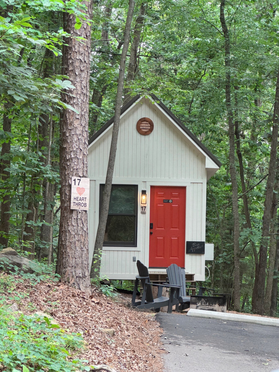 A small building with a red door is set back into the woods at ReTreet Resort & Spa. It has a sign that reads "Heart Throb."