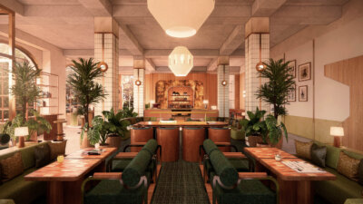 Modern restaurant interior with green cushioned chairs, wooden tables, potted plants, geometric lighting, and a central bar area in the background—an inviting space reminiscent of the chic ambiance found in boutique hotels favored by discerning travel enthusiasts.