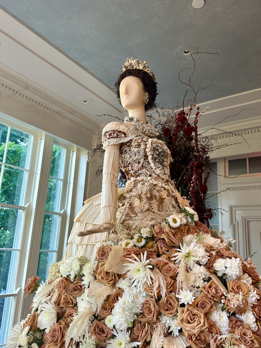 Fleurs de Villes: Cheekwood’s Latest Exhibit is a Must-See - 6 A mannequin in an ornate gown made of dried flowers and plants stands indoors near large windows at Cheekwood, as part of a stunning floral exhibit, with floral and vine decorations evoking Gilded-Age elegance in the background.