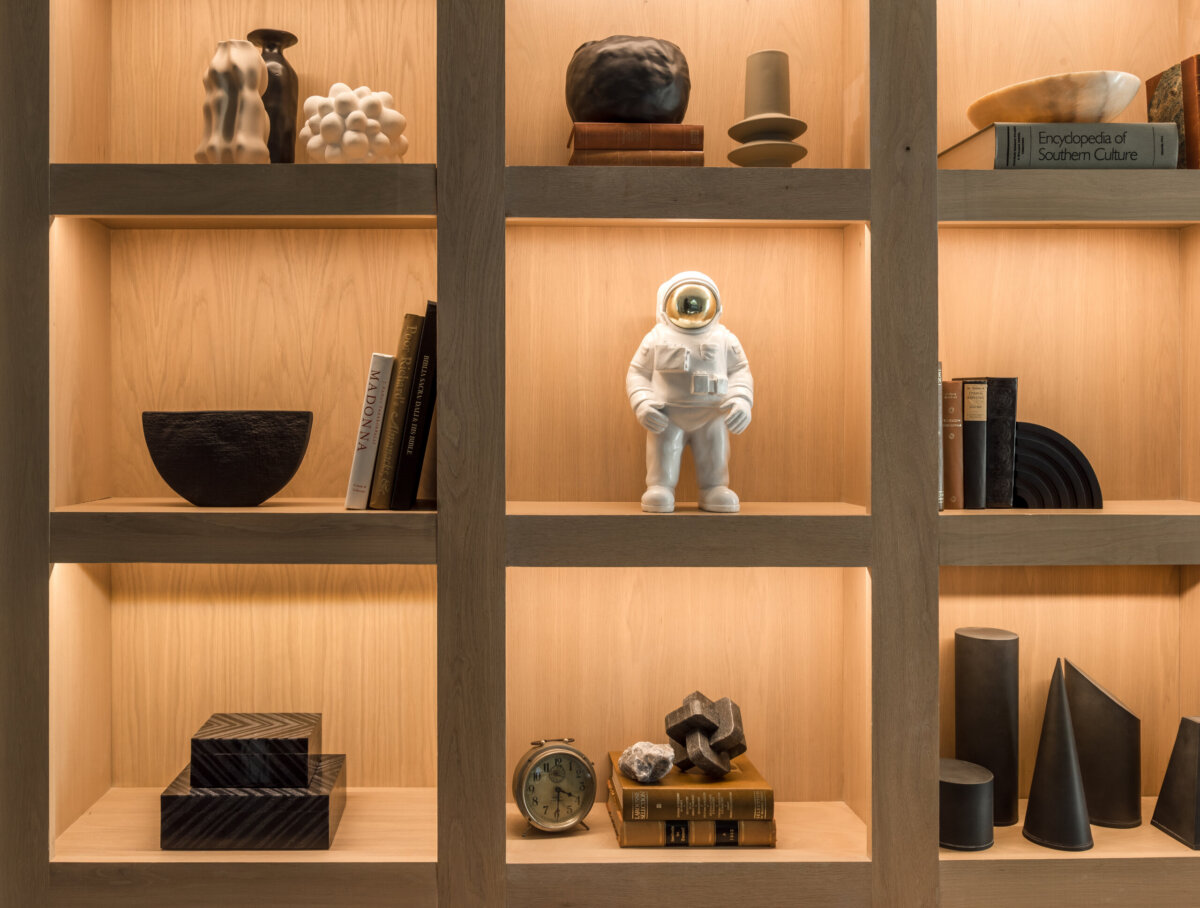 There's a Graffiti-Covered Bust in This Nashville Home, and It Works - 13 Wooden shelves adorned with decorative objects, books, a ceramic astronaut figure, an old-fashioned clock, geometric sculptures, and a book titled “Encyclopedia of Southern Culture” reflect the eclectic character of this striking Nashville home.