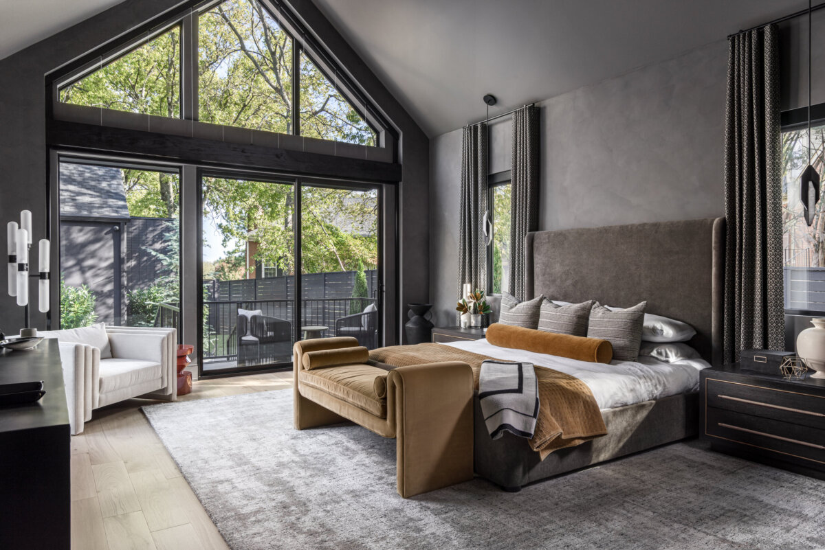 There's a Graffiti-Covered Bust in This Nashville Home, and It Works - 14 Modern bedroom with large windows, vaulted ceiling, a bed with neutral bedding, tan bench, armchair, and an outdoor patio visible through glass doors, creating a striking space reminiscent of a modern art gallery in a Nashville home.