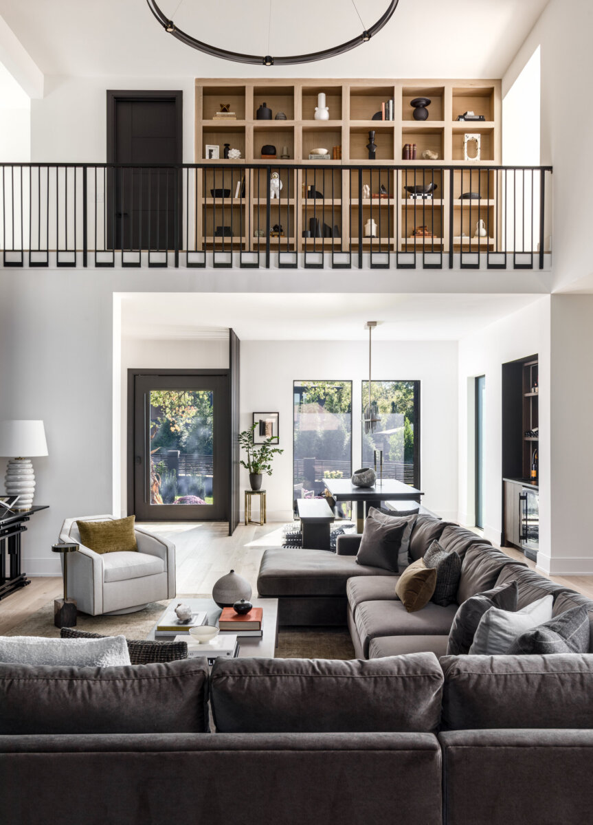 There's a Graffiti-Covered Bust in This Nashville Home, and It Works - 5 Modern living room with a large gray sectional sofa, armchair, coffee tables, built-in shelving on the upper level, and large windows letting in natural light—this striking home evokes the feel of a modern art gallery while offering comfort and style in every detail.