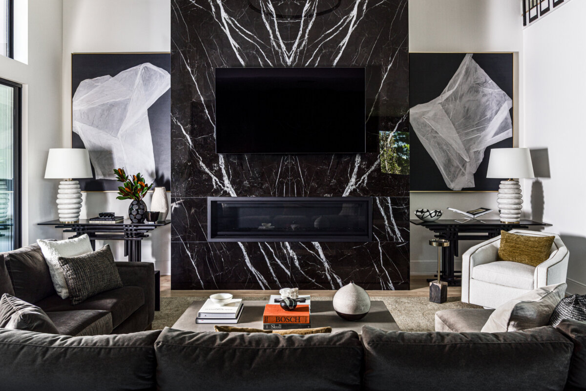 There's a Graffiti-Covered Bust in This Nashville Home, and It Works - 6 Modern living room in a striking home with black marble fireplace, wall-mounted TV, abstract art reminiscent of a modern art gallery, two side tables with white lamps, and gray seating arranged around a beige rug.