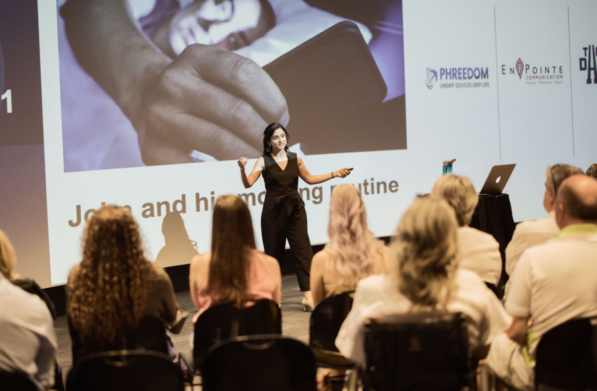 This Nashville Doctor Helps Families Disconnect to Reconnect - 4 Nidhi Gupta gives a presentation to an audience in a conference room, standing in front of a large screen displaying an image and text.