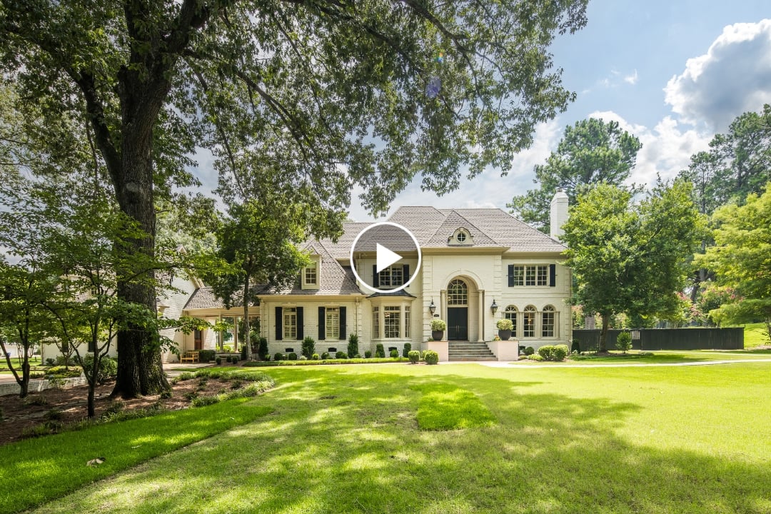Elegant Germantown TN real estate featuring a large two-story white house with columns, arched windows, and a manicured lawn at 2340 Duntreath Rd, surrounded by tall trees under a partly cloudy sky.