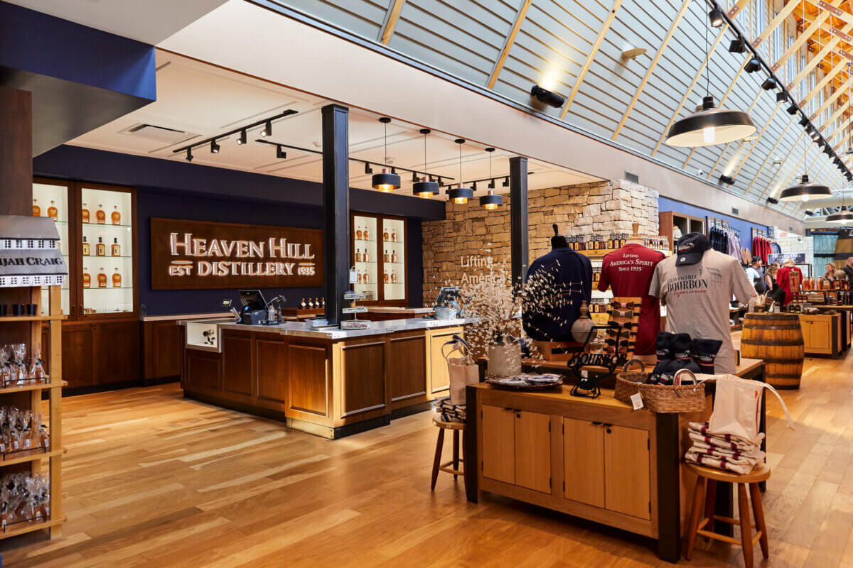 Interior of Heaven Hill Distillery gift shop with wooden floors, merchandise displays, bottles on shelves, and a large Heaven Hill sign on the wall—one of the Favorite Stops for those eager to experience authentic Southern Spirits and Raise A Glass to timeless tradition.