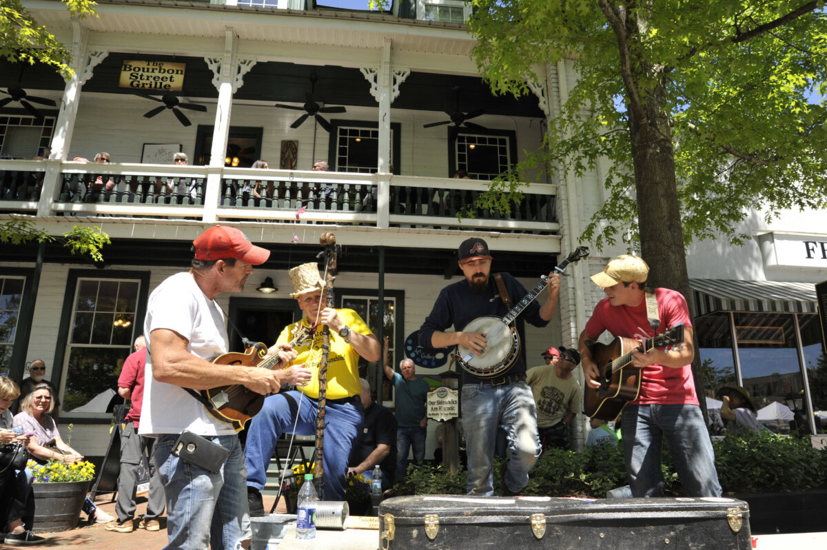 5 Destinations Where Southern Charm Thrives - 5 A four-member band plays string instruments outdoors in front of a crowd.