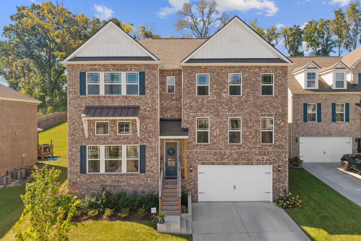 Two-story brick house with multiple windows, a front porch, and a white double garage door, set on a green lawn with a driveway at 1121 Parklawn Dr in Nashville.